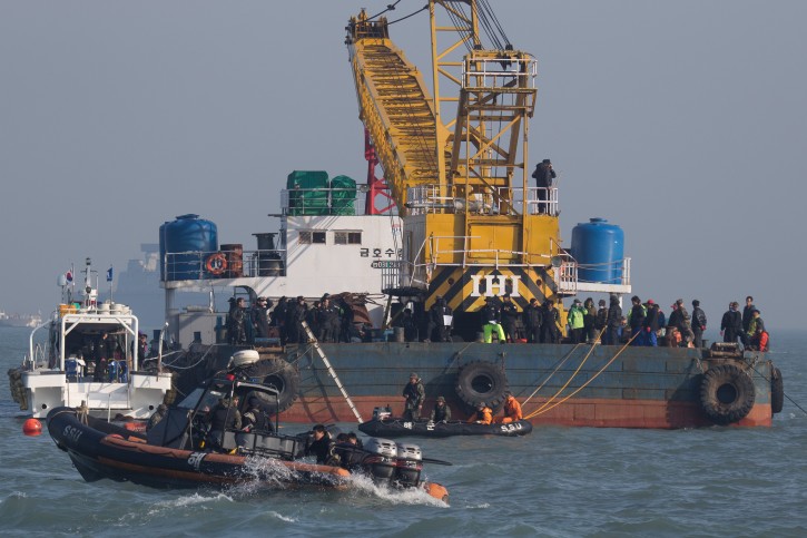 In this Tuesday, April 22, 2014, searchers and divers look for people believed to have been trapped in the sunken ferry Sewol in the water off the southern coast near Jindo, south of Seoul, South Korea. One by one, coast guard officers carried the newly arrived bodies covered in white sheets from a boat to a tent on the dock of this island, the first step in identifying a sharply rising number of corpses from the South Korean ferry that sank nearly a week ago. (AP Photo/Korea Pool) 