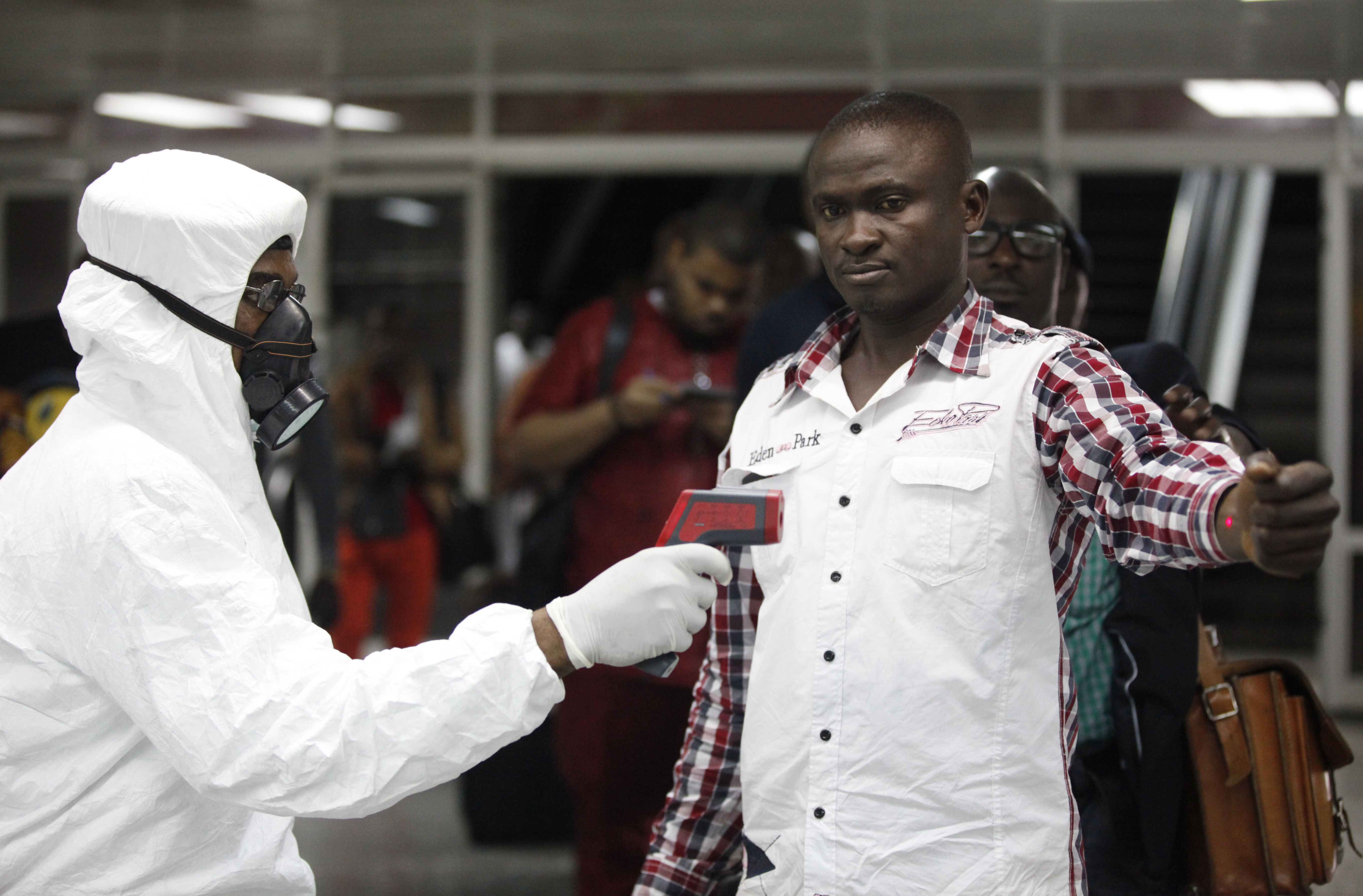 A Nigerian port health official uses a thermometer on a worker at the arrivals hall of Murtala Muhammed International Airport in Lagos, Nigeria, Wednesday, Aug. 6, 2014. (AP Photo)