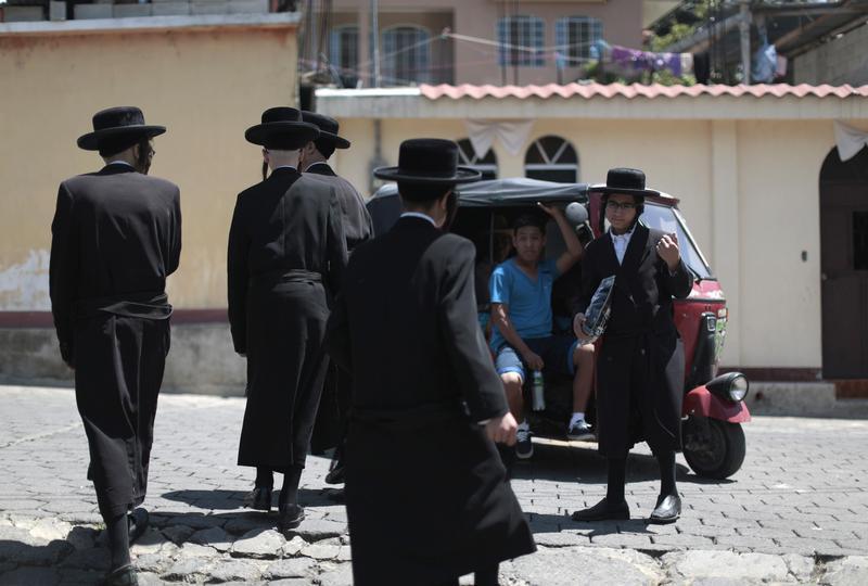 FILE - Members of a Jewish community walk near a motor taxi in the village of San Juan La Laguna August 24, 2014. Reuters