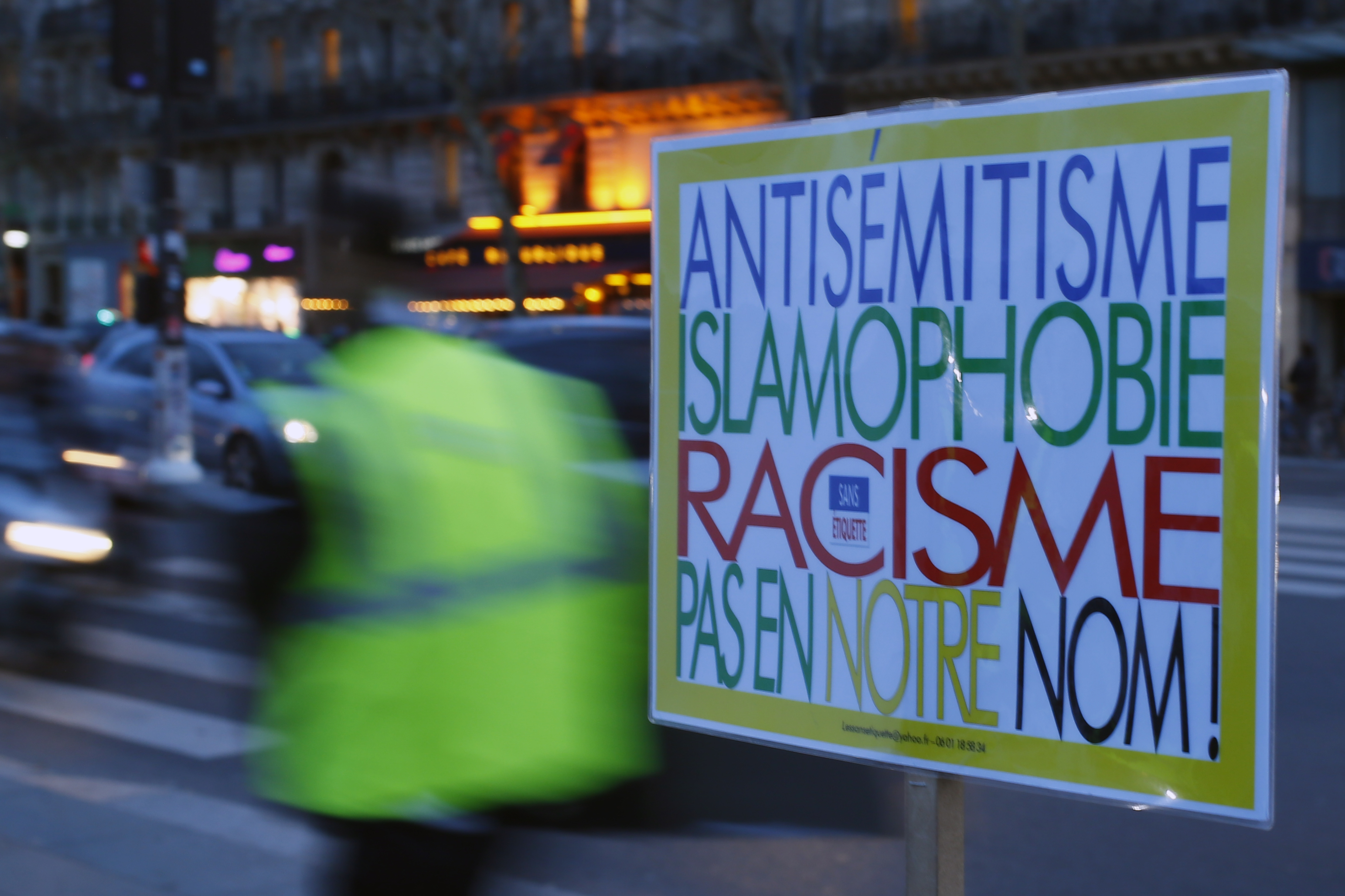 A poster reading "Anti-Semitism, Islamophobia, Racism, Not in Our Name" during a gathering decrying anti-Semitism at Place de la Republique in Paris, Monday, Feb. 18, 2019 amid an upsurge in anti-Semitism in France. It reached a climax last weekend with a torrent of hate speech directed at a distinguished philosopher during a march of yellow vest protesters, adding to questions about the radicalized fringes of the movement hidden within French society and troubling the nation. (AP Photo/Francois Mori)