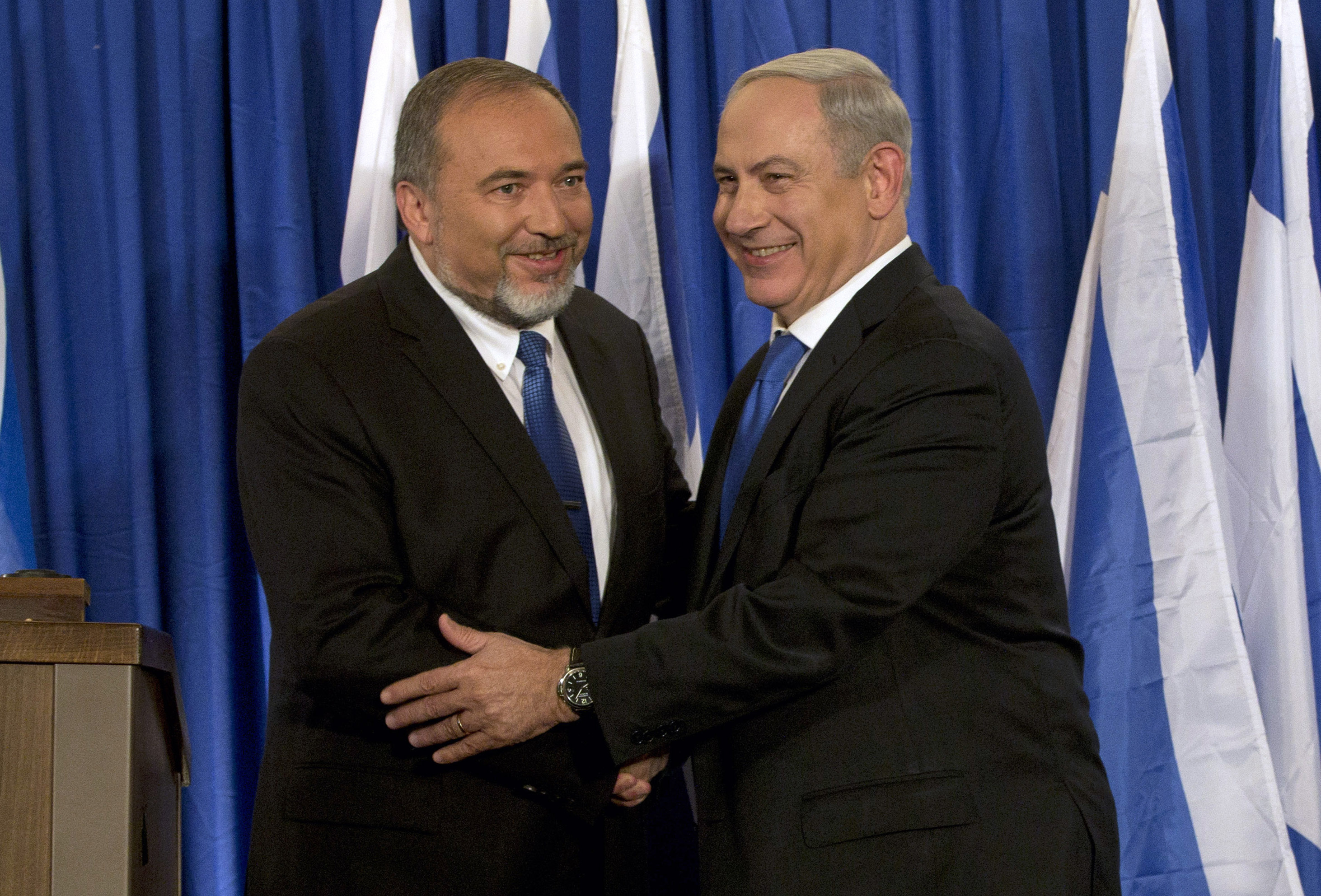 FILE - In this Oct. 25, 2012 file photo, Israeli Prime Minister Benjamin Netanyahu, right, and former Israeli Defense Minister Avigdor Lieberman shake hands in front of the media after giving a statement in Jerusalem. (AP Photo/Bernat Armangue, File)
