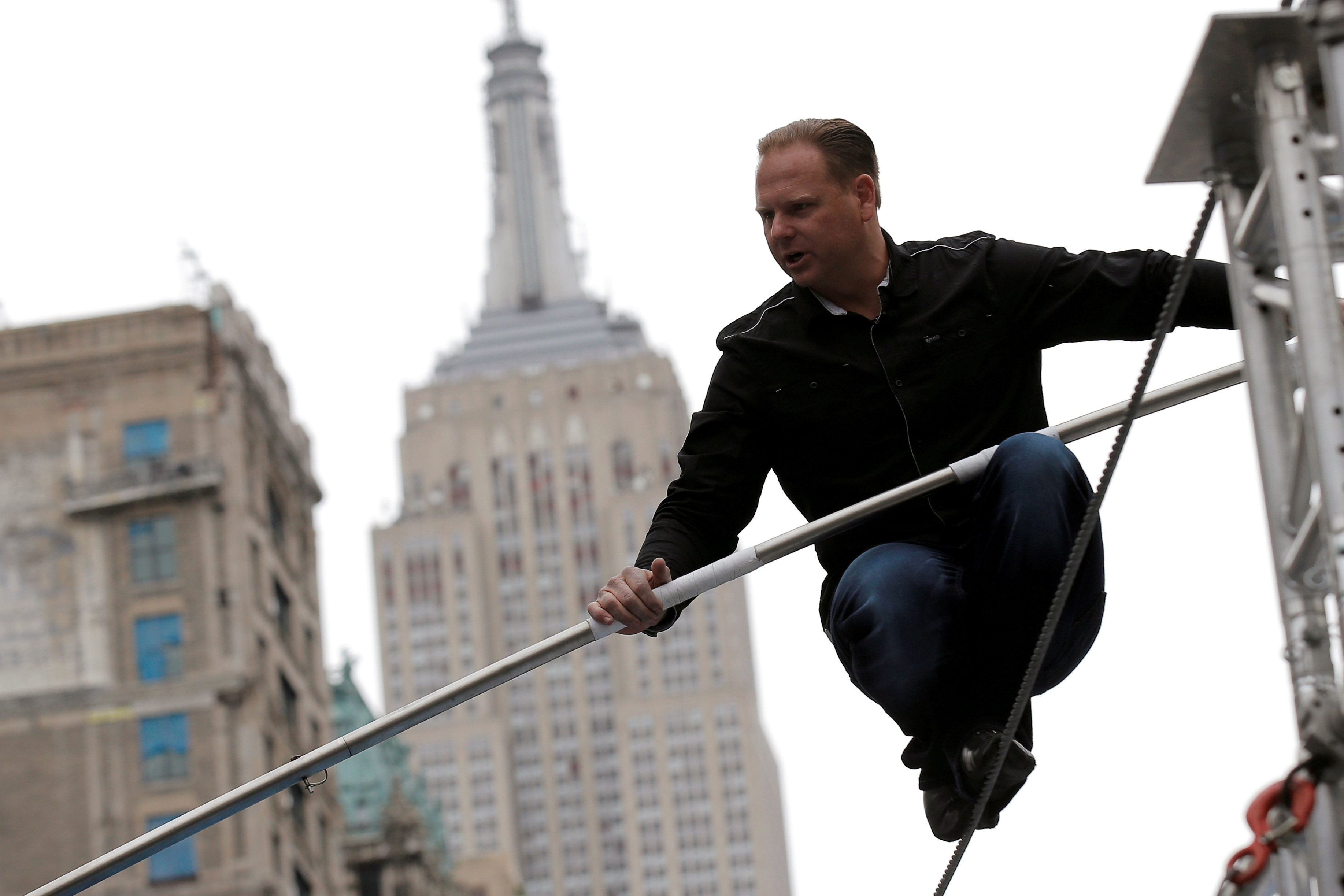 FILE - Aerialist Nik Wallenda walks a tightrope during a promotional event in midtown Manhattan, with the Empire State Building behind him, in New York City, U.S., May 17, 2016. REUTERS/Brendan McDermid -/File Photo