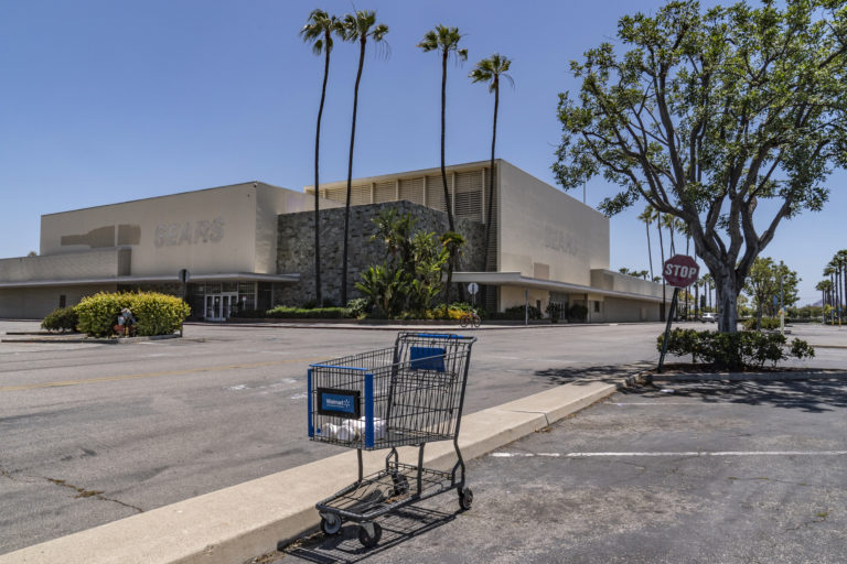This Thursday, May 27, 2021, photo shows an empty shopping cart in an empty parking lot at the closed Sears in Buena Park Mall in Buena Park, Calif. California state lawmakers are grappling with a particularly 21st-century problem: What to do with the growing number of shopping malls and big-box retail stores left empty by consumers shifting their purchases to the web. A possible answer in crowded California cities is to build housing on these sites, which already have ample parking and are close to existing neighborhoods. Even before the pandemic, big-box retail stores struggled to adapt as more people began buying things online. In 2019, after purchasing Sears and Kmart, Transformco closed 96 stores across the country, 29 in California. (AP Photo/Damian Dovarganes)