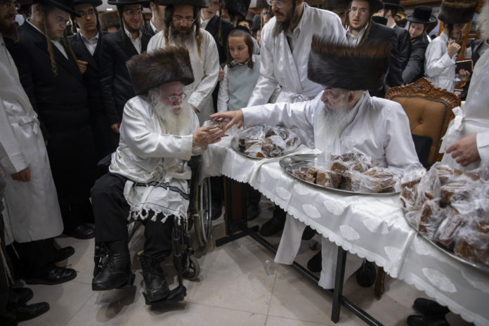 Rabbi Aharon Biderman gives cakes to his followers just before the start of the Jewish holiday of Yom Kippur, in the city of Beit Shemesh, Israel, Wednesday, Sept. 15, 2021. Yom Kippur is Judaism's day of atonement, when devout Jews ask God to forgive them for their transgressions and refrain from eating and drinking, attending intense prayer services in synagogues. (AP Photo/Oded Balilty)