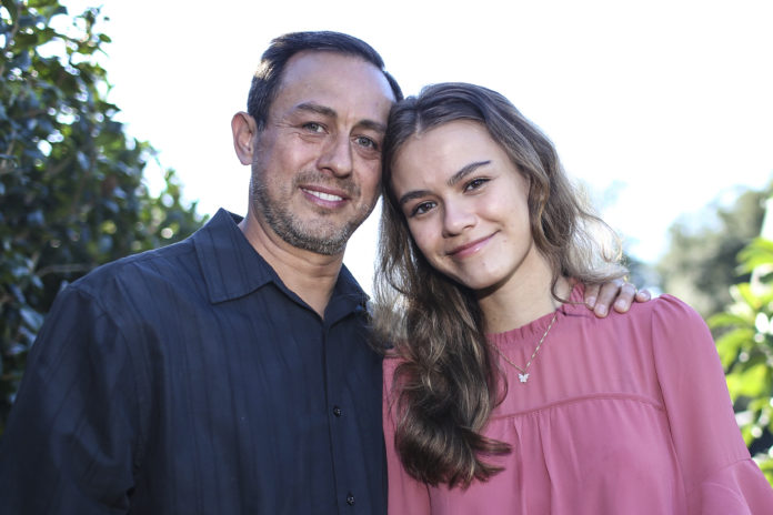 Portrait of Mitch Arbelaez and his daughter Jayden in Jacksonville, Fla., Wednesday, Oct. 13, 2021. Banned from the Florida hospital room where her mother lay dying of COVID-19, Jayden Arbelaez pitched an idea to construction employees working nearby. The workers gave the 17-year-old a yellow vest, boots, a helmet and a ladder to climb onto a section of roof so she could look through the window and see her mother, Michelle Arbelaez, alive one last time. (AP Photo/Gary McCullough)