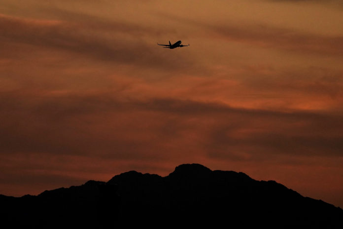 A passenger jet is silhouetted against the sky at dusk as it takes off from Sky Harbor Airport, Saturday, April 2, 2022, in Phoenix. Airlines have cancelled more than 3,300 U.S. flights this weekend and delayed thousands more, citing weather in Florida and other issues. (AP Photo/Charlie Riedel)