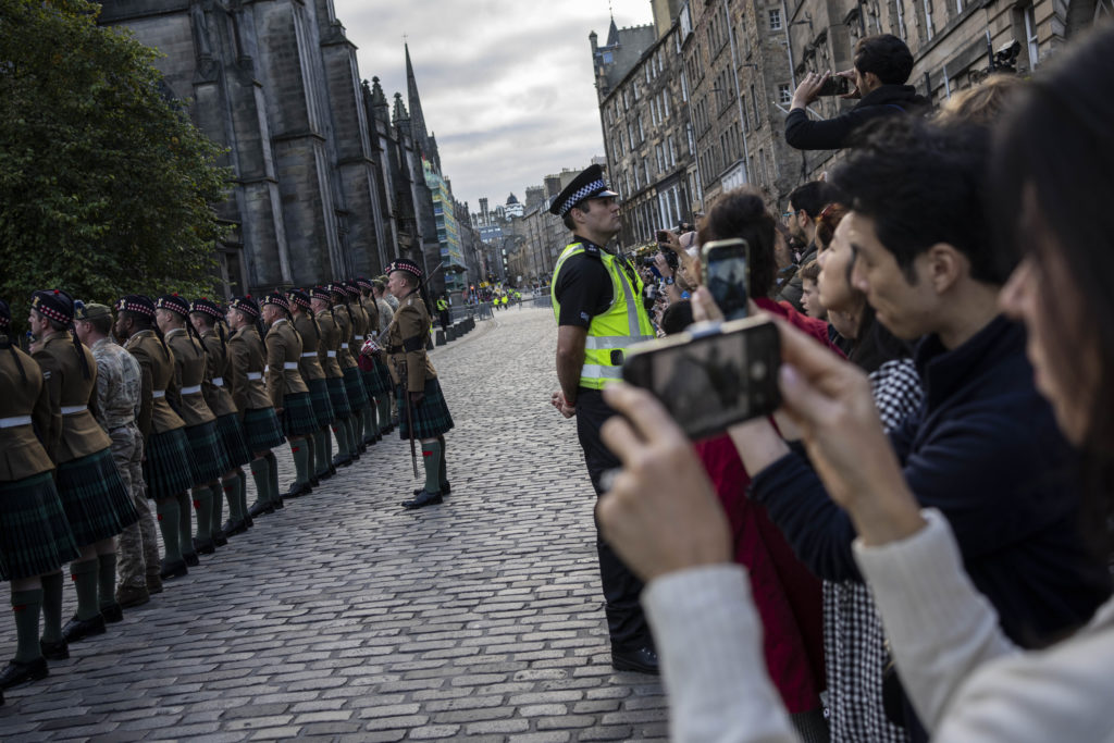 People watch members of the 4th Battalion Royal Regiment of Scotland during the proclamation rehearsal outside St Giles’ Cathedral, in Edinburgh, Scotland, Saturday, Sept. 10, 2022. Queen Elizabeth II, Britain’s longest-reigning monarch and a rock of stability across much of a turbulent century, died Thursday Sept. 8, 2022, after 70 years on the throne. She was 96. (AP Photo/Bernat Armangue)