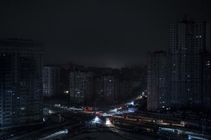 Cars drive past residential blocks which were de-energized after a Russian rocket attack in Kyiv, Ukraine, Wednesday, Nov. 23, 2022. (AP Photo/Evgeniy Maloletka)